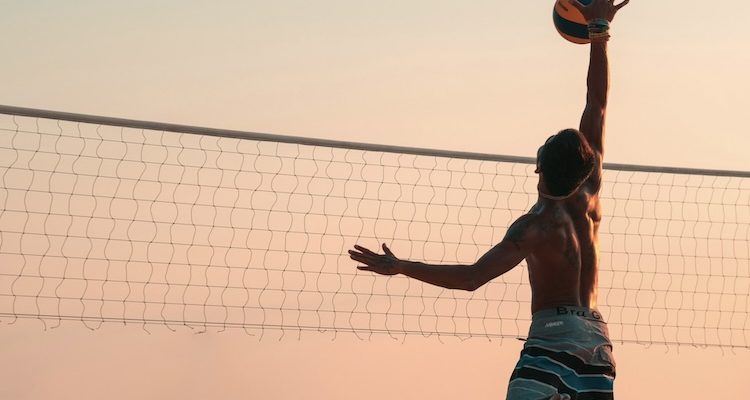 Volleyball player fully extended for a spike, capturing the constant drive behind perfectionism in athletes